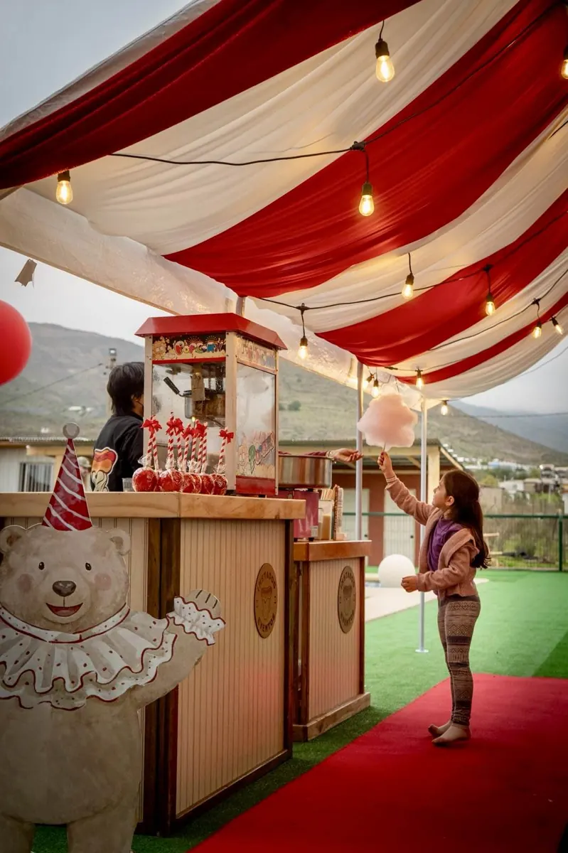Stand Instadog con carpa roja, máquina de palomitas y algodón de azúcar en un cumpleaños